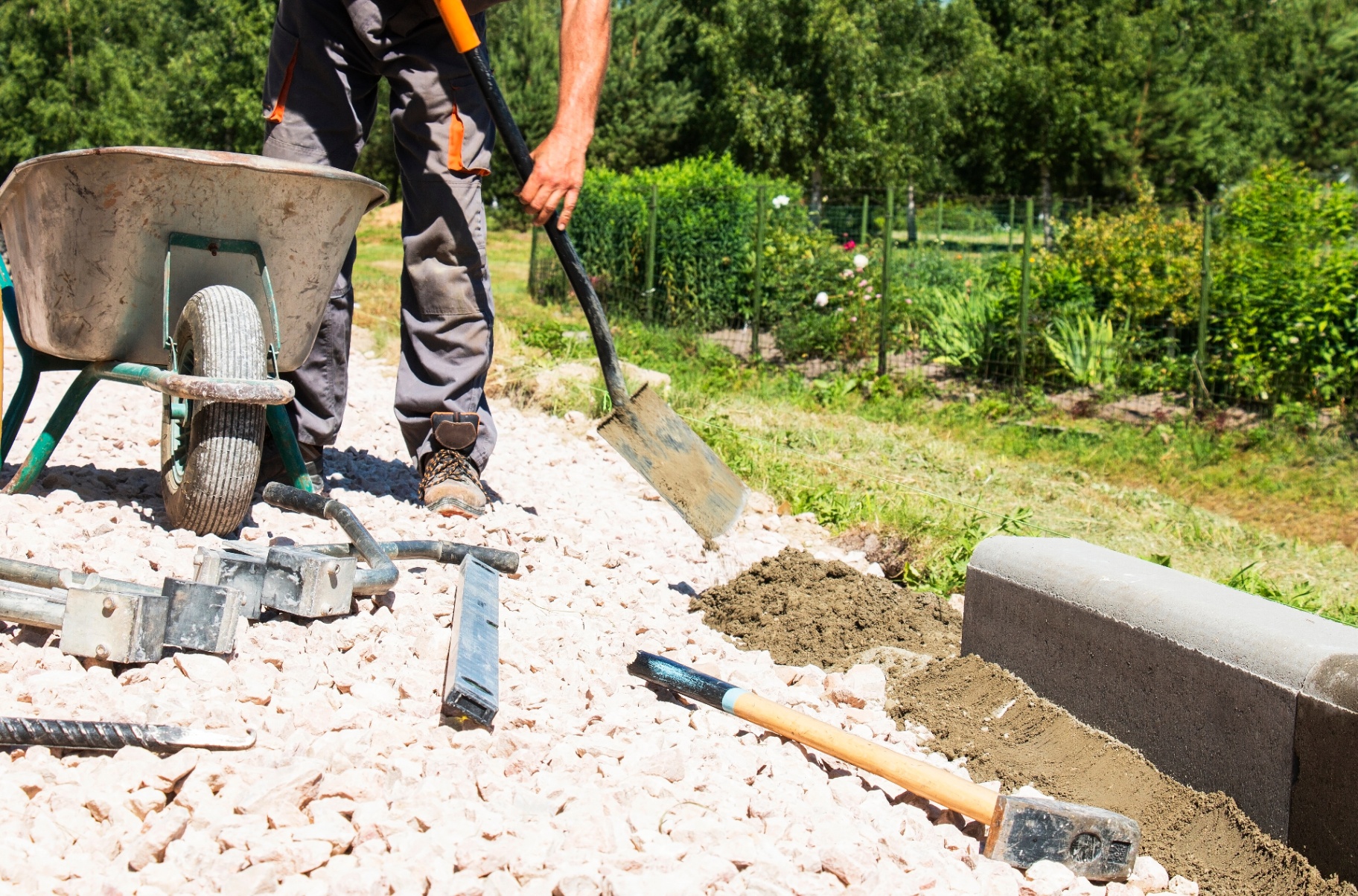 Handwerker bei Gartenarbeiten mit Schubkarre und Spaten
